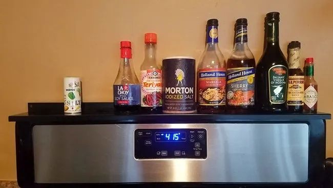A reviewer's photo of the black shelf displaying pantry staples like soy sauce and Tabasco.