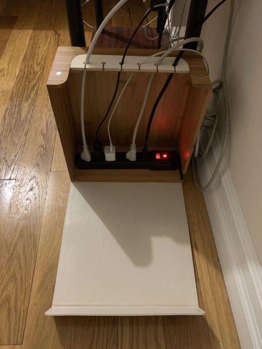 Cords are plugged into a power strip and neatly organized within a box, reducing the mess and clutter.