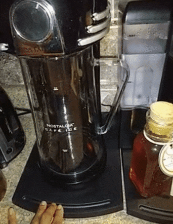 A coffee maker being smoothly moved across a counter with the help of a sliding caddy.