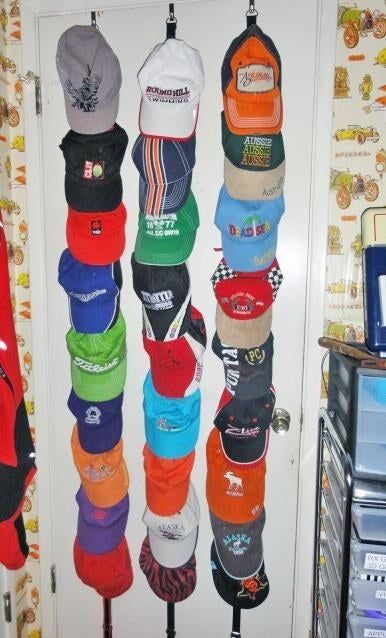 The three-section organizer with various baseball hats hanging on the back of a door