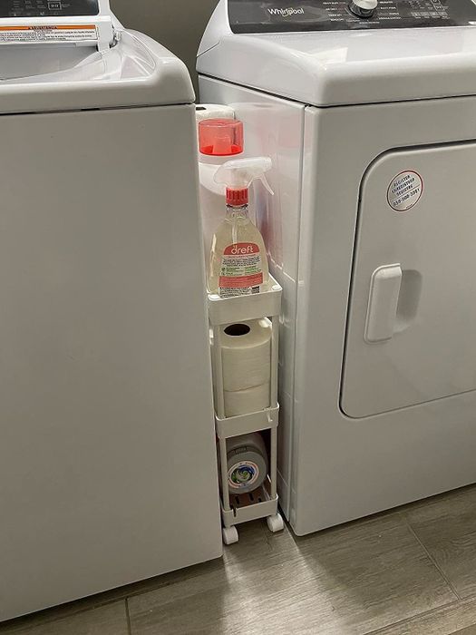A reviewer's image of the cart positioned between their washer and dryer, showcasing its space-saving design.