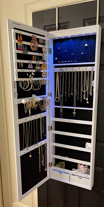 The same reviewer reveals the interior of the storage mirror, displaying neatly hung jewelry, showcasing its dual functionality.