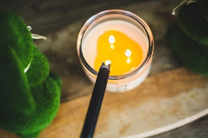 a reviewer using an electric lighter to ignite a candle