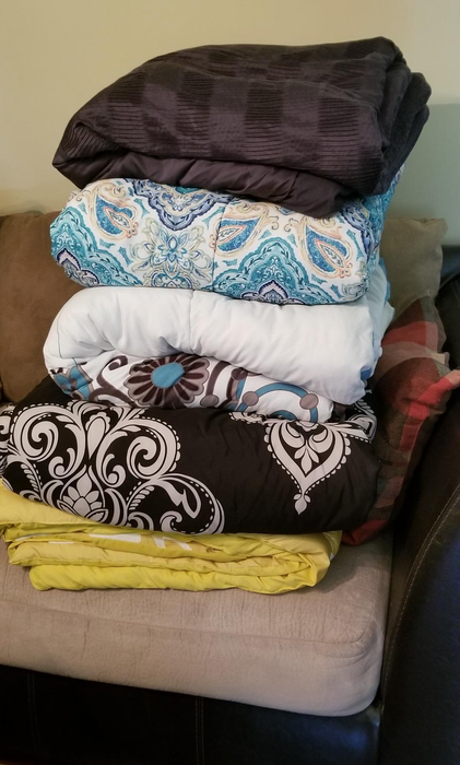 reviewer's stack of five bulky comforters showing their large size