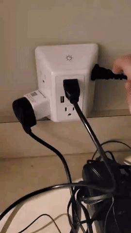 A reviewer turning the light on and off while several items are plugged into the charger.
