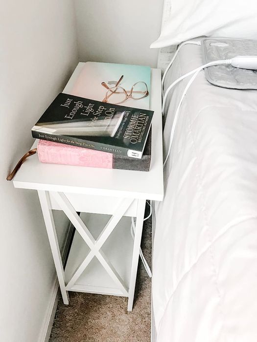 a reviewer's white end table with books neatly placed on top