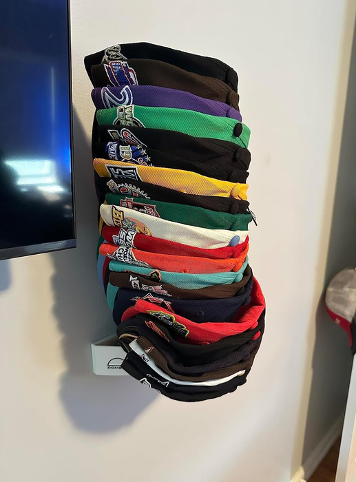 A white cap holder on the wall, displaying 20 hats in an organized fashion