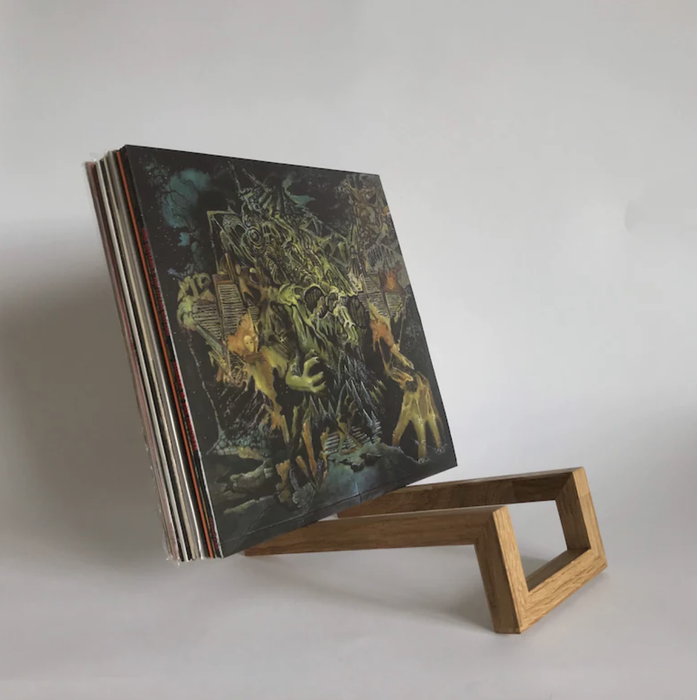 A wooden vinyl rack holding approximately 10 records