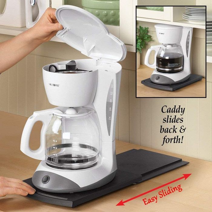 A black caddy placed under a coffee maker, demonstrating its ability to slide effortlessly forward and backward.