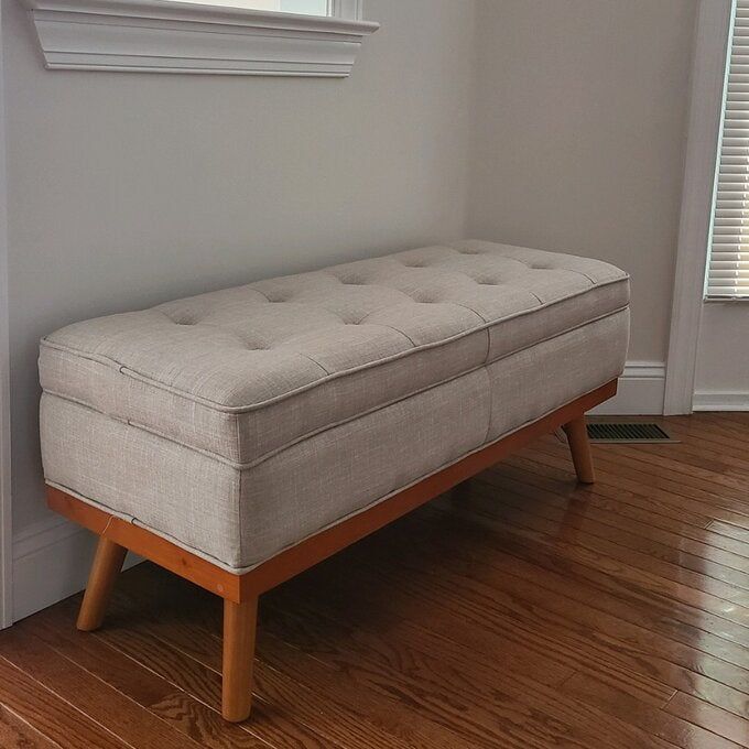 A reviewer's gray storage bench featuring wooden legs, blending functionality with a sleek design.