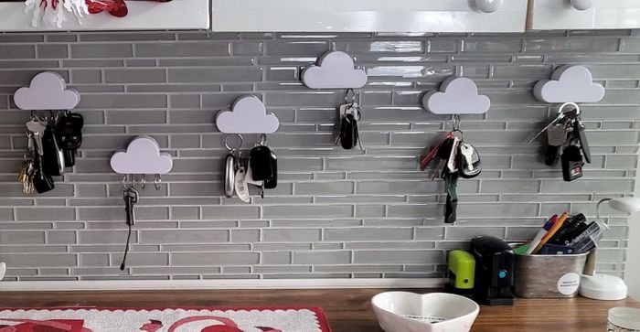 The reviewer shows six cloud-shaped key holders mounted on their kitchen backsplash, each holding a variety of keys.