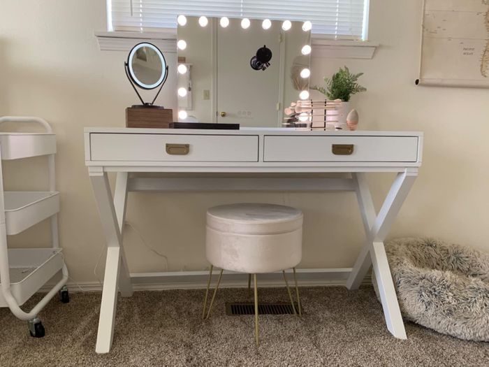 A photo of the reviewer's cream-colored ottoman placed in front of their vanity.