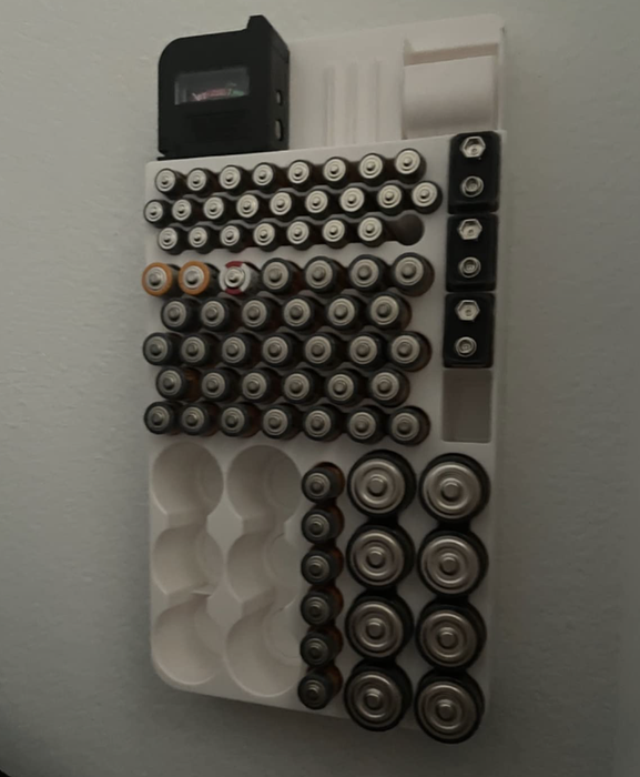 A reviewer's photo showing the battery organizer and tester mounted on the wall.