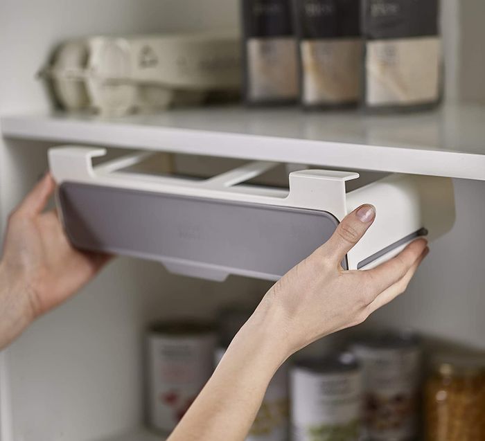 A model pulls a spice storage shelf, which is mounted horizontally, from the bottom of a cabinet.