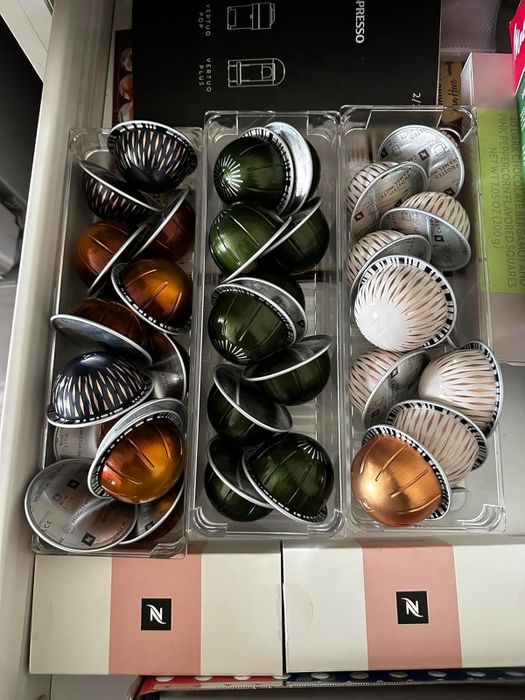 A reviewer's Nespresso coffee pods neatly organized in three clear plastic trays inside a drawer.