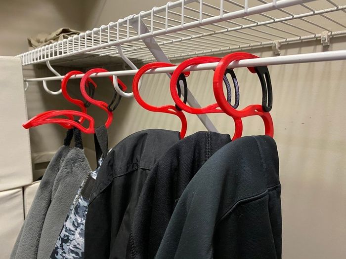 Five hoodie hangers with cozy hoodies draped over them, hanging neatly in a closet.