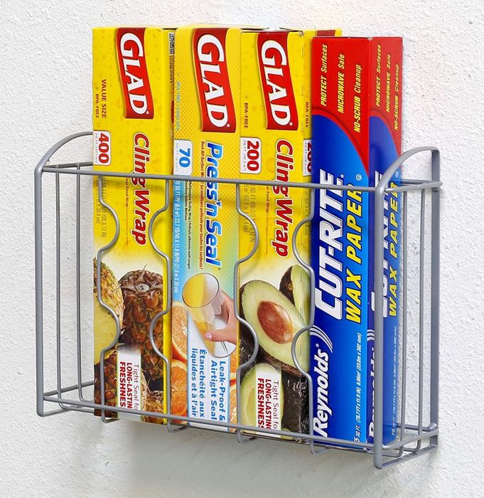 A mounted shelf on the wall filled with boxes of cling wrap and aluminum foil