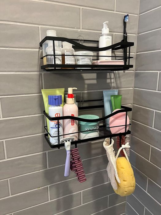 Reviewer shows black adhesive shelves mounted on a shower wall, filled with various products.