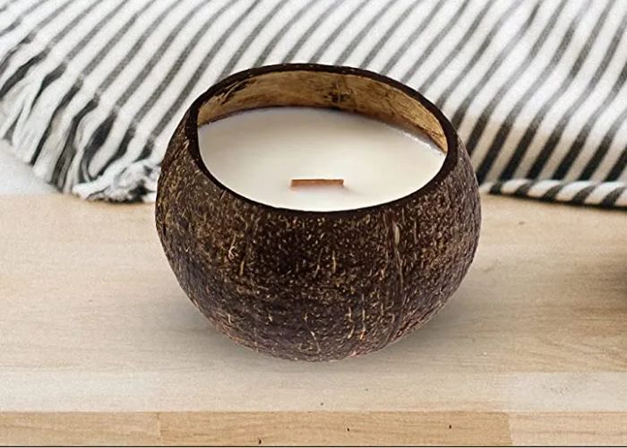 White candle nestled inside a coconut, complete with a wood wick