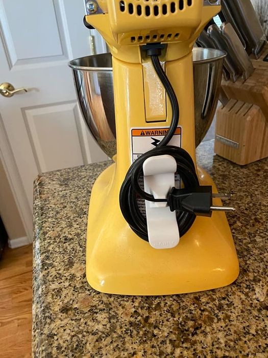 A reviewer’s yellow stand mixer with a cord organizer attached, and the cord neatly wrapped around it.