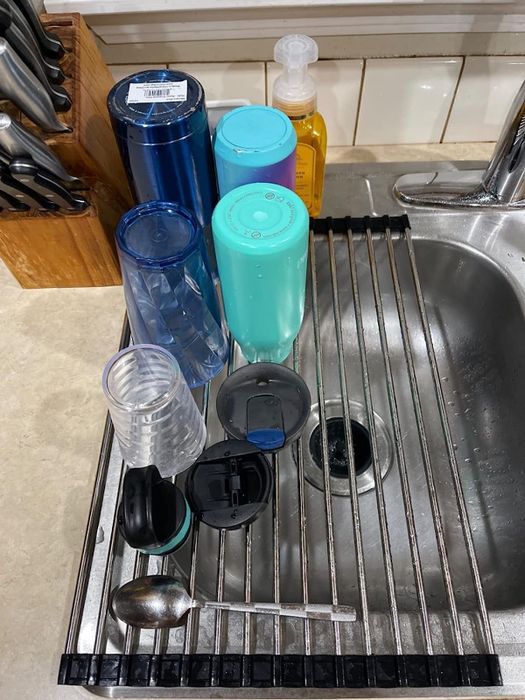 A reviewer demonstrates the rack in use, holding freshly washed dishes.