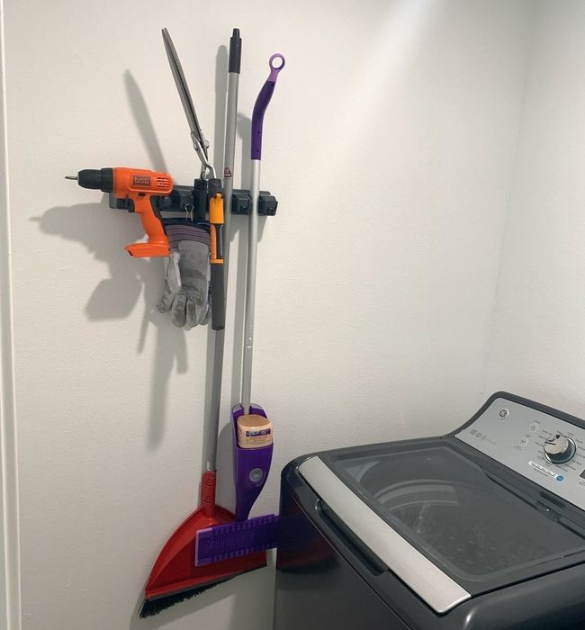 Reviewer photo showing the organizer holding a broom, Swiffer, and even a drill attached to it