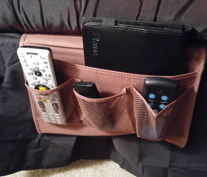 Reviewer photo showing the bedside caddy with remotes and a book inside.