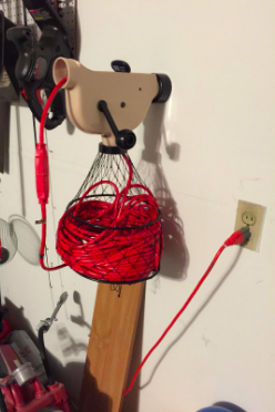 A reviewer's cord bundler with a basket mounted on a wall