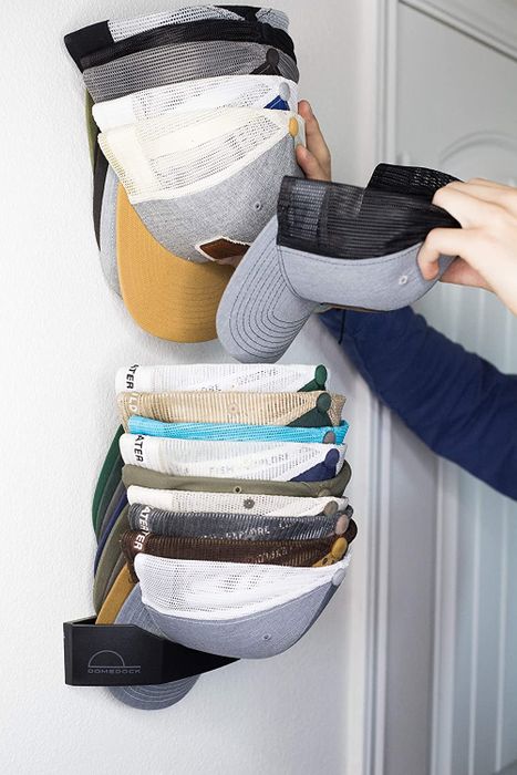 Someone pulling a cap out from the wall-mounted organizer