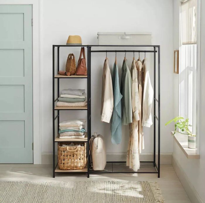 An open wardrobe is neatly organized with folded clothes, a basket, bags, and several garments hanging on the rack. Soft sunlight filters through a nearby window, bathing the space in warmth.