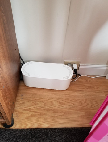 A reviewer's white cable management box with cables securely hidden inside.