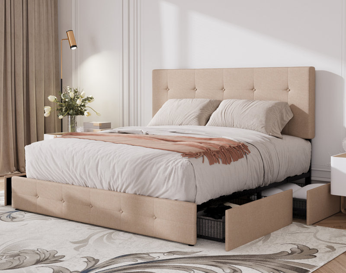 A stylish bedroom featuring a beige upholstered storage bed, white bedding, and a bedside table adorned with a vase of flowers.