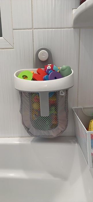 A reviewer’s bath toy storage bag filled with toys and attached to the bathroom wall.