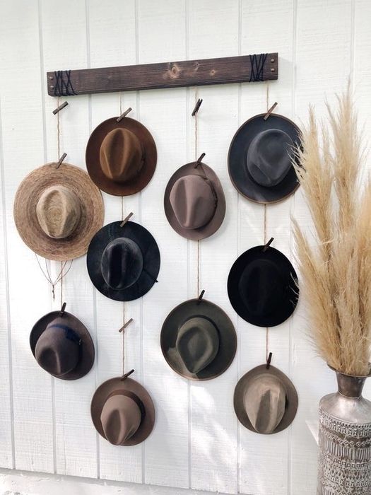 A hanging hat organizer with colorful fedoras clipped to pins hanging from ropes