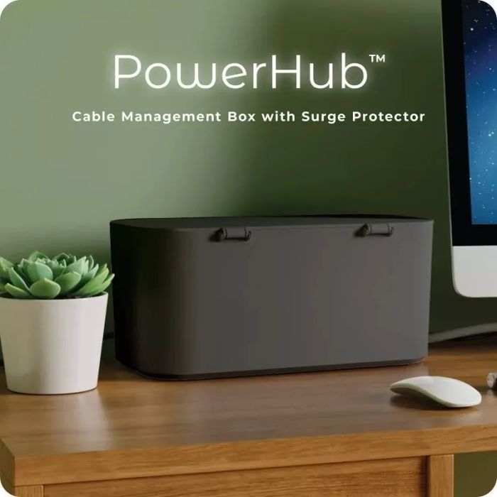 PowerHub cable management box with surge protector sits on a desk beside a plant and computer screen. Perfect for keeping cables organized and protected