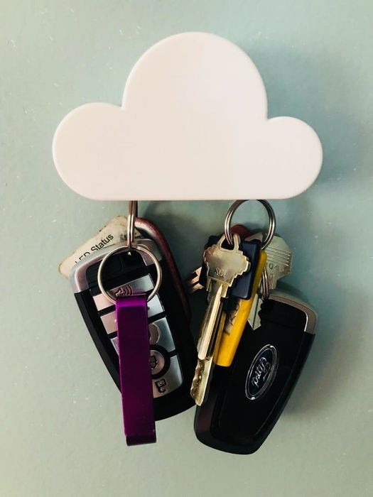 A minimalist cloud-shaped magnet mounted on a wall, holding two sets of car keys.
