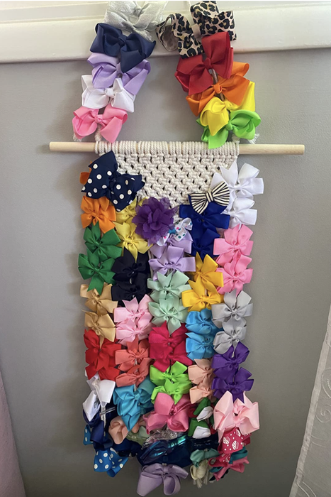A reviewer's photo showing the macramé hair accessory holder filled with numerous hair ties and bows