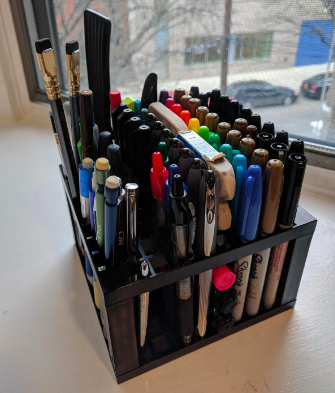 A review photo where the organizer cube is filled with an assortment of markers, pens, pencils, and a few paint brushes.