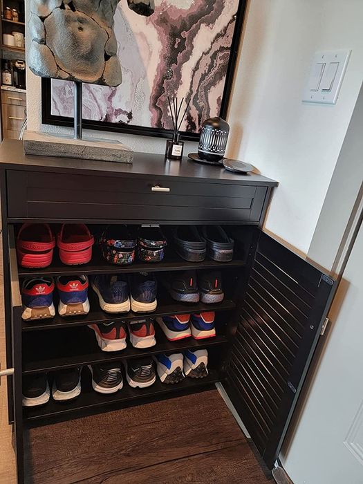 the cabinet opened, displaying four shelves, each holding three pairs of adult shoes