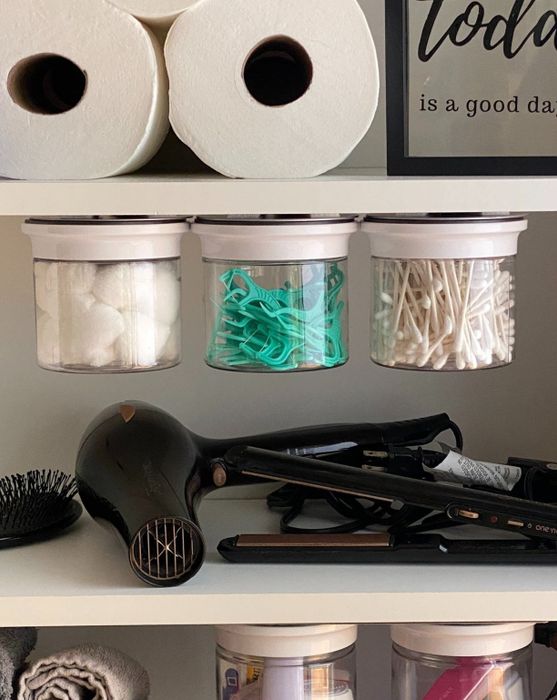 Three canisters being used to store floss, cotton balls, and swabs, showcasing their versatility.