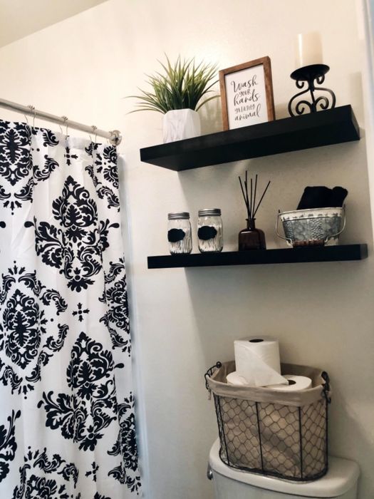 Another reviewer displaying two sleek black shelves mounted in their bathroom, demonstrating a practical storage solution.