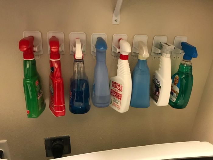 A reviewer's wall featuring eight spray bottles, each securely mounted on a separate holder