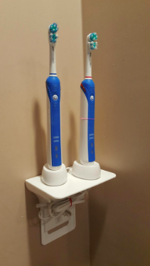 A reviewer’s photo showing an outlet shelf holding two electric toothbrushes