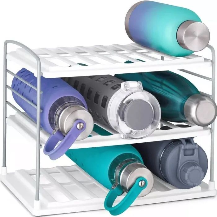Six different reusable water bottles rest horizontally on a three-tiered white shelf