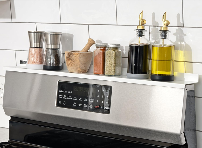 An image of a stove with a shelf mounted on top, holding various spices.