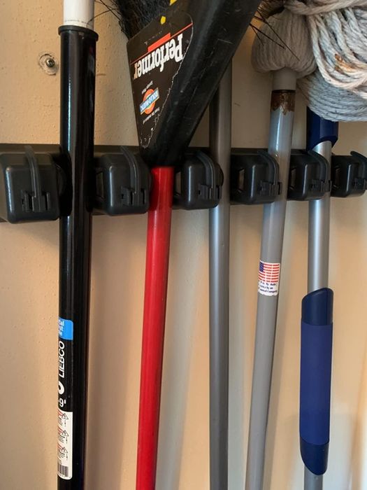 A close-up shot from the reviewer, showcasing the organizer holding brooms and mops in place.
