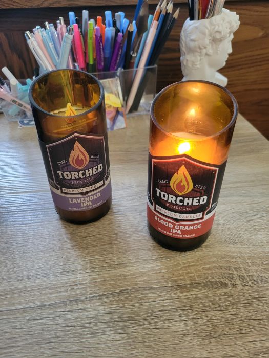 An unlit lavender candle next to a lit blood orange candle