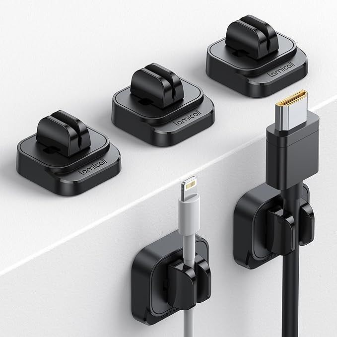 Five sleek black cable organizers attached to a table, neatly holding HDMI cables.