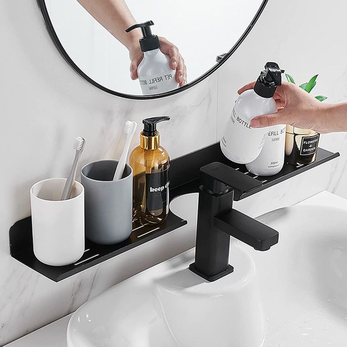 The black shelf holding soap and toothbrushes, demonstrating its practical use in organizing bathroom essentials.