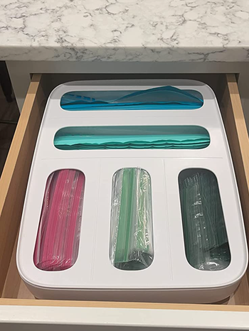 A white dispenser with five slots, each holding bags in various sizes.